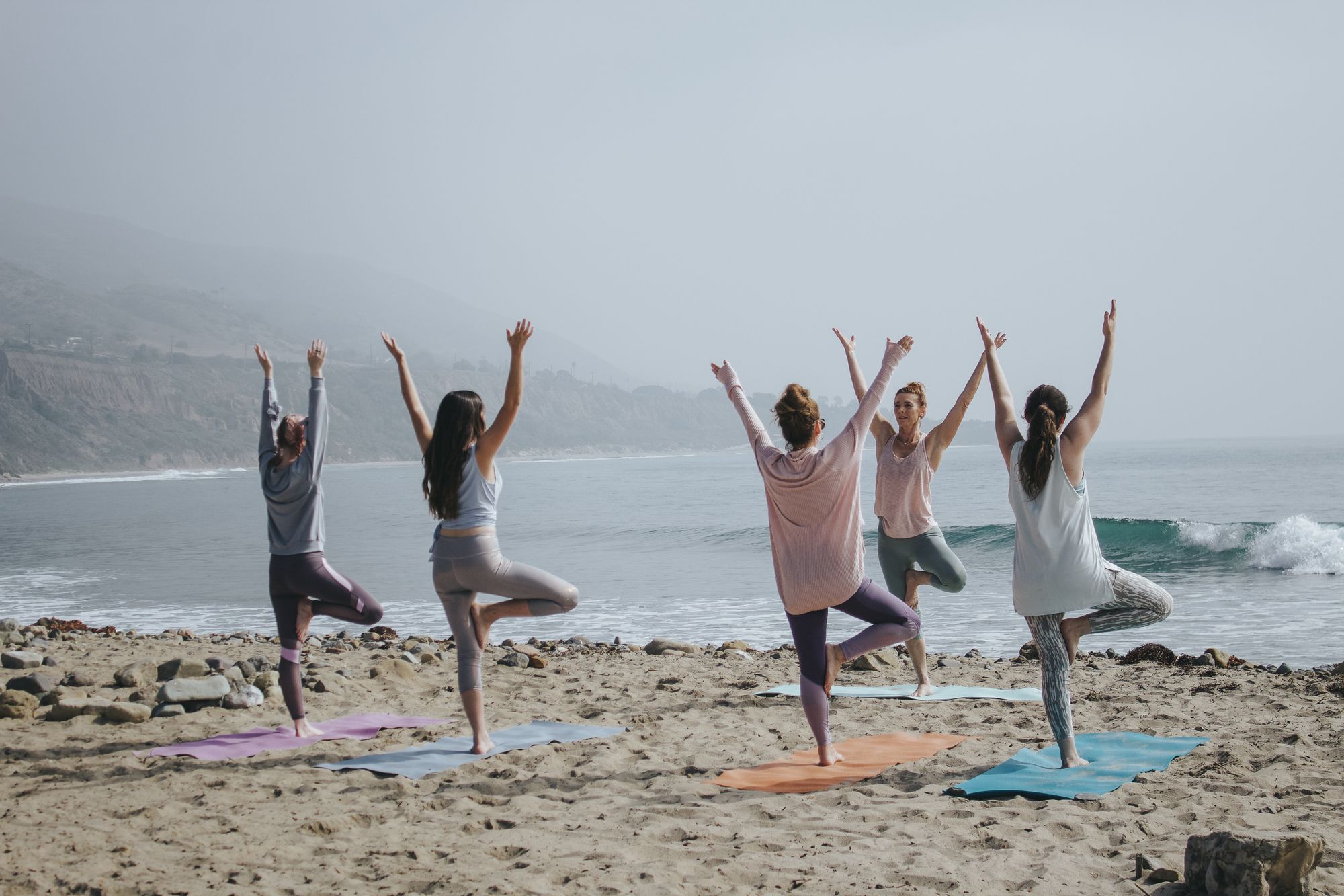 Practicing how to teach yoga with a small group of yoga students at the beach