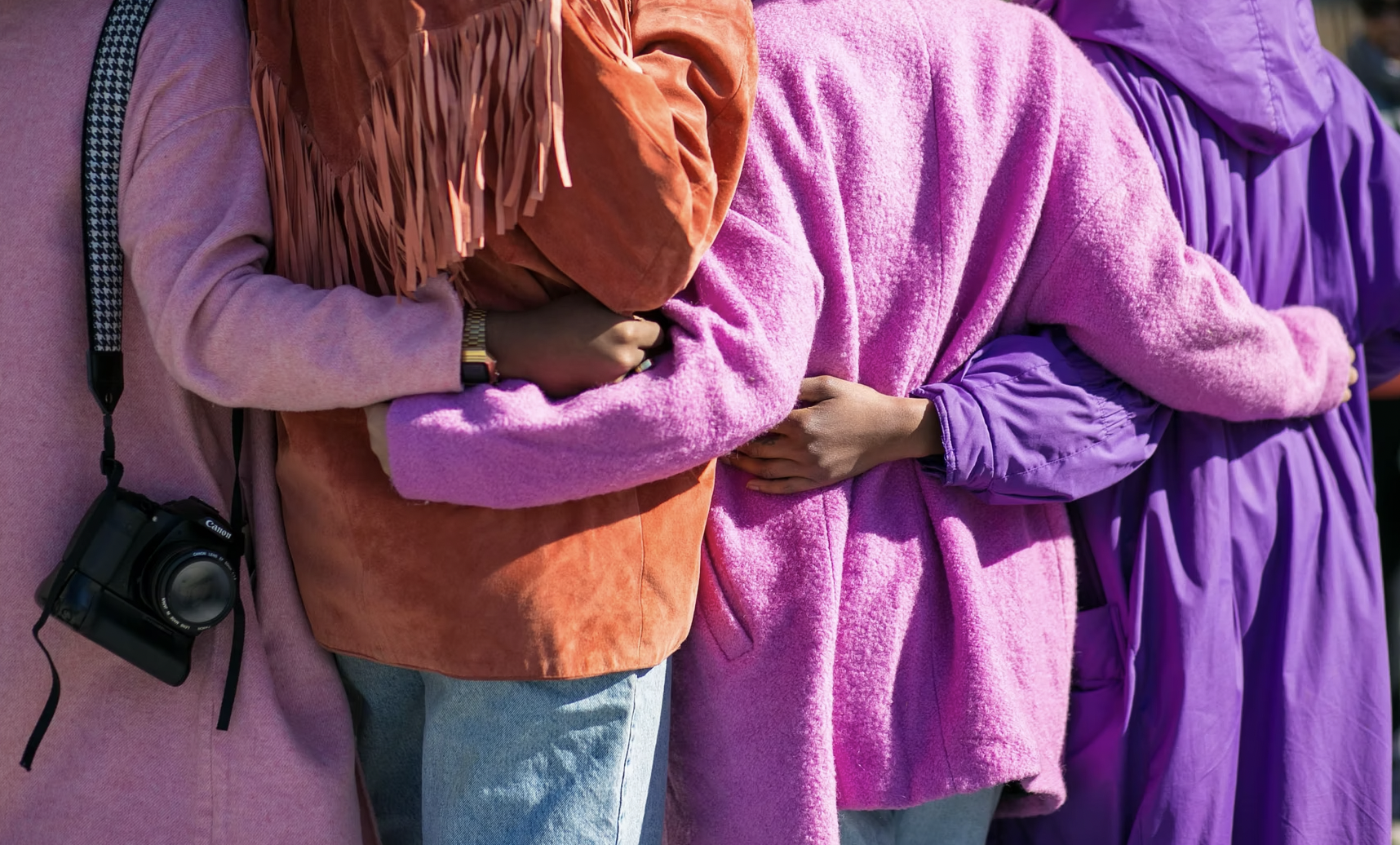 Women wrapping their arms around each other harmoniously.